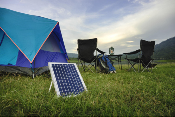 Compact solar charger powering mobile and camera near river in nature