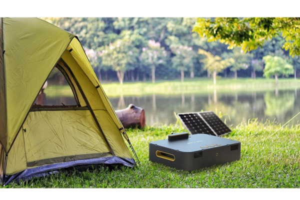 Traveler using portable solar panel to charge laptop in forest outdoor workspace